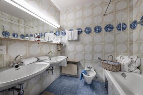 a bathroom with two sinks and a toilet and a tub at Hotel St. Oswald in Bad Kleinkirchheim