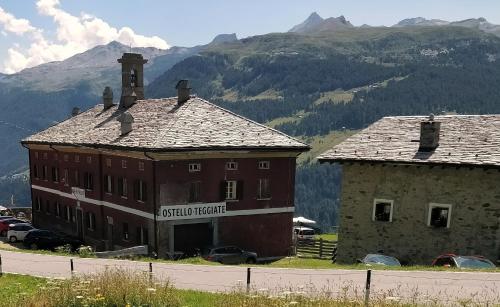 an old building with a sign on it next to a mountain at Rifugio Teggiate in Madesimo