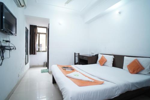 Schlafzimmer mit einem großen weißen Bett und einem Flachbild-TV in der Unterkunft Hotel Laxmi Villa Palace in Jaipur