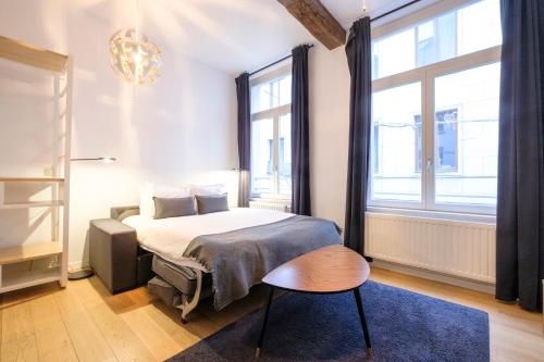 - une chambre avec un lit, une chaise et des fenêtres dans l'établissement The Doms Flats, à Bruxelles