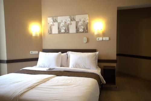 a bedroom with a large bed with white sheets and pillows at Hotel La Riva in Siófok