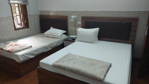 um quarto com 2 camas e uma janela em Nhà nghỉ sao mai 2 em Hanói