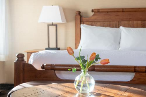 a vase with flowers on a table in front of a bed at Best Western Plus Waterbury - Stowe in Waterbury