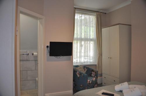 a room with a bed and a television on the wall at Hotel Peppers in Torquay