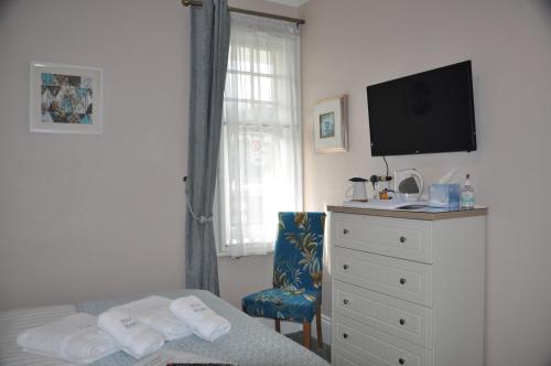a bedroom with a bed and a dresser with a television at Hotel Peppers in Torquay