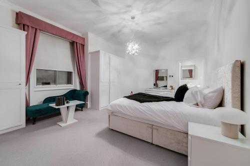 een witte slaapkamer met een groot bed en een groene stoel bij Luxury London 3 Bedroom Duplex with Pool Table 4 in Londen