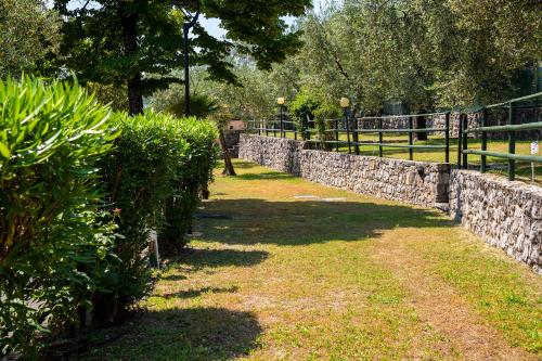 una pared de piedra con arbustos y una valla en Camping Fontanelle, en Moniga del Garda