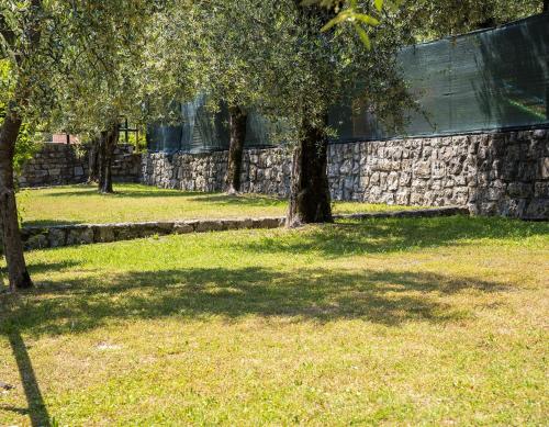 grupa drzew w parku obok kamiennej ściany w obiekcie Camping Fontanelle w mieście Moniga