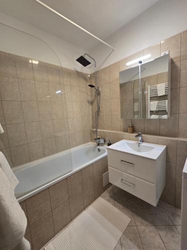 een badkamer met een bad, een wastafel en een spiegel bij Júlia Apartman Kaposvár*** in Kaposvár