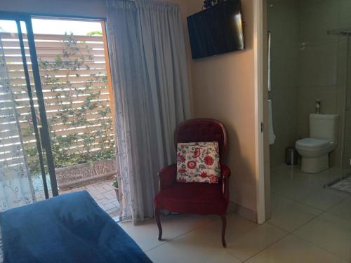 a red chair in a room with a window at SONHOS dreams Self catering apartment Unit 1 in Bloemfontein