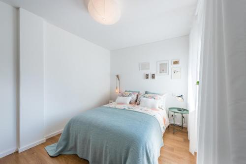 a white bedroom with a bed with a blue blanket at GuestReady - Chic and cozy getaway in Porto