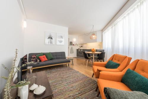 a living room with orange chairs and a couch at GuestReady - Chic and cozy getaway in Porto