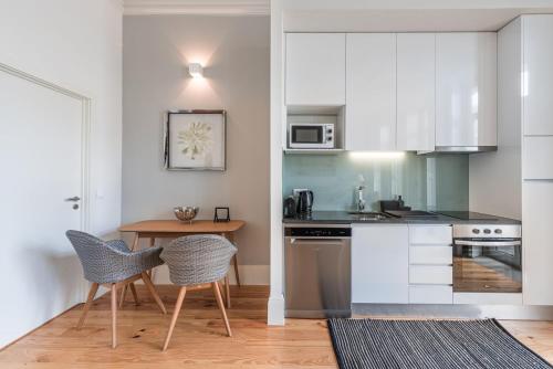 eine Küche mit weißen Schränken und einem Tisch und Stühlen in der Unterkunft GuestReady - Seaside getaway in Porto in Porto