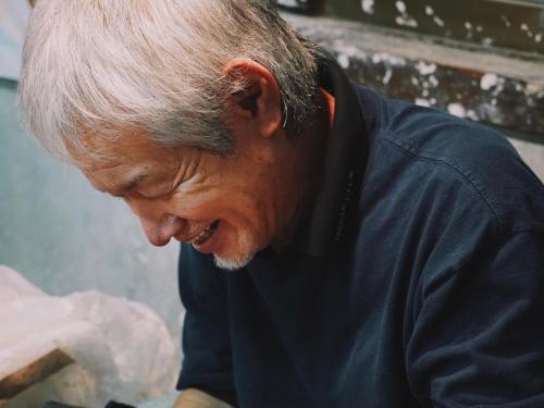 an older man is smiling while looking at something at ホテルコンドミニアム土花土花 in Onna