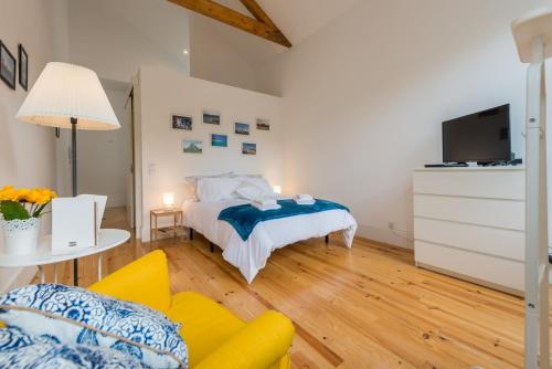 een slaapkamer met een bed, een bank en een tv bij GuestReady - Quaint comfort near Clérigos Tower in Porto