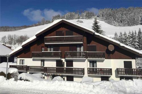 a building covered in snow with snow covered trees at Appartement plein sud montagne et lacs in Habère-Poche