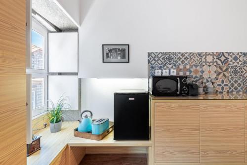 una cucina con frigorifero nero e forno a microonde di GuestReady - Trendy city central studio a Porto