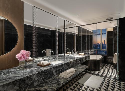 a bathroom with two sinks and two mirrors at Conrad Urumqi in Ürümqi