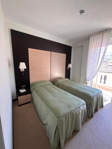 a hotel room with two beds and a window at HOTEL LUDOVICO ARIOSTO in Castelnuovo di Garfagnana