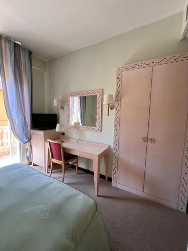 a bedroom with a bed and a desk and a mirror at HOTEL LUDOVICO ARIOSTO in Castelnuovo di Garfagnana