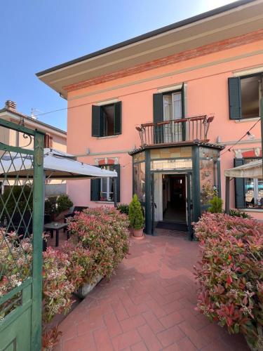 a pink building with a balcony and a patio at HOTEL LUDOVICO ARIOSTO in Castelnuovo di Garfagnana