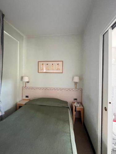 a bedroom with a green bed and two tables at HOTEL LUDOVICO ARIOSTO in Castelnuovo di Garfagnana