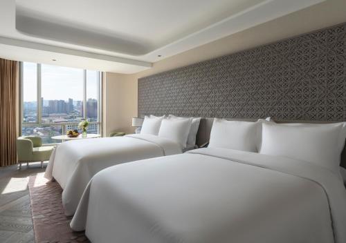 two white beds in a hotel room with a window at Conrad Urumqi in Ürümqi