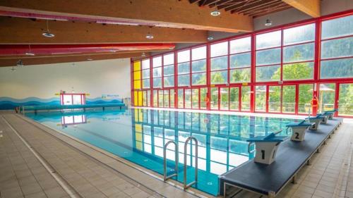 a large swimming pool with benches in a large building at Bella Italia & EFA Village in Forni Avoltri