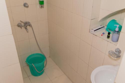 a bathroom with a green bucket in a shower at Homestay Urmil Basant in Jaipur