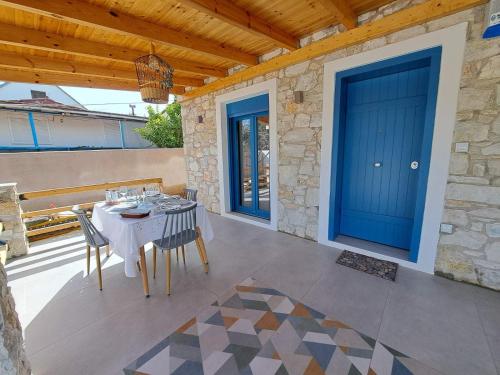 a patio with a table and chairs and a blue door at A GEORGE Luxury house in Artemida
