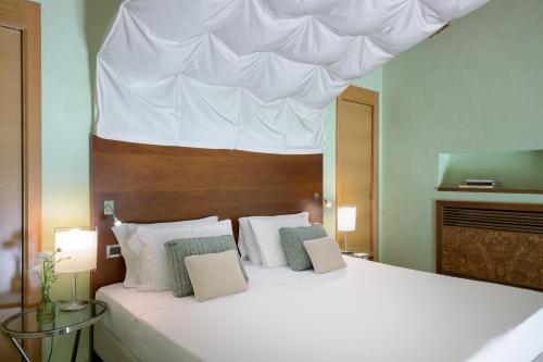 a bedroom with a large white bed with a white canopy at Hotel Ilaria in Lucca