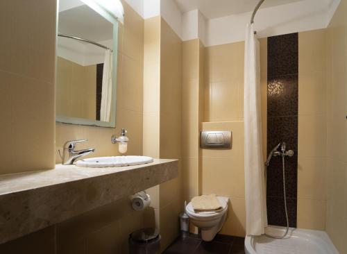 ein Badezimmer mit einem Waschbecken, einem WC und einem Spiegel in der Unterkunft Golden Rose Suites in Kolimvárion