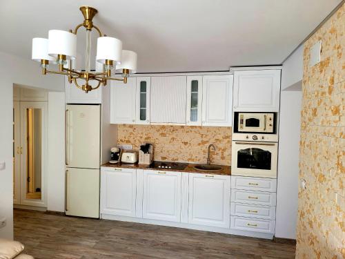 - une cuisine blanche avec des placards blancs et un lustre dans l'établissement R&R Apartament, à Ocna-Mureşului