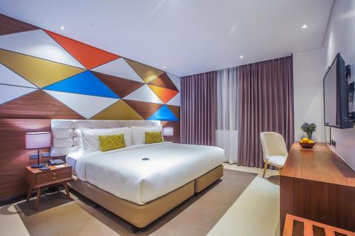 a bedroom with a large bed with a colorful wall at Summit Hotel Naga in Naga