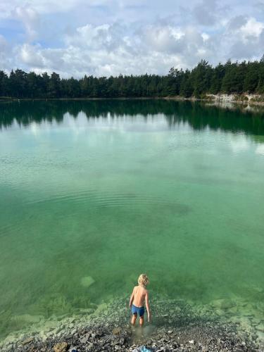 Un uomo in piedi in un corpo d'acqua di Mysig tomt med stugor i Rute a Lärbro