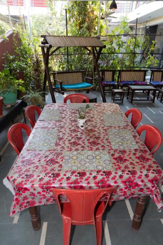a table with red chairs and a red flower patterned table sidx sidx at Homestay Urmil Basant in Jaipur