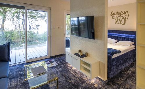 a bedroom with a bed and a tv and a balcony at Apartamenty WRZOS w Perłowej Przystani in Sianozety