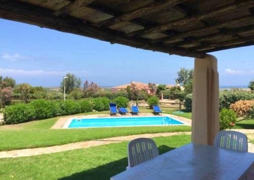 a patio with a table and chairs and a pool at Villa Claudia piscina privata in Stintino