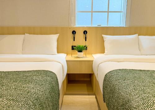 two beds in a room with a window at Urbanwood Hung Hom in Hong Kong