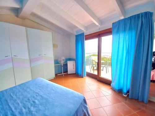 a bedroom with a blue bed and a large window at Villa del Tramonto - Piscina privata in Stintino