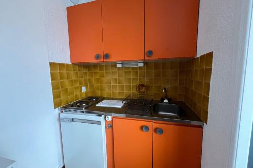 eine kleine Küche mit orangefarbenen Schränken und einem Waschbecken in der Unterkunft Charming accommodation on the Port of Gruissan in Gruissan