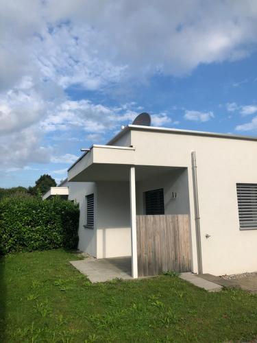 a white house with a wooden door in a yard at CROWN LIVING Design Apartment - gratis Parkplatz - WLan - Küche - Self Check-in in Altach