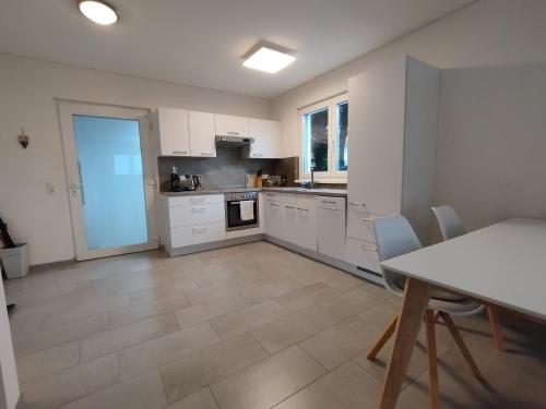 una cocina con armarios blancos y una mesa con sillas. en CROWN LIVING Design Apartment - gratis Parkplatz - WLan - Küche - Self Check-in, en Altach