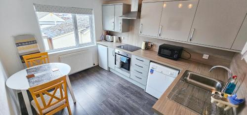 a kitchen with white cabinets and a sink and a table at Lovat 2 Bedroom Apartment - Inverness in Inverness