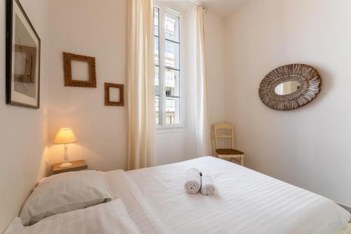 - une chambre dotée d'un lit blanc avec deux chaussures dans l'établissement Freres PradignacLAT1101, à Cannes