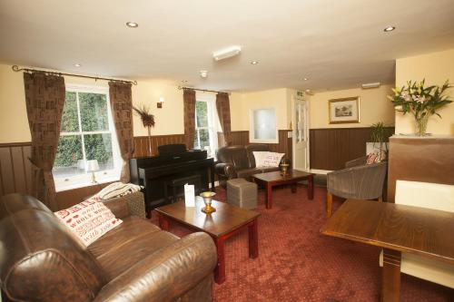 a living room with leather furniture and a piano at The Five Bells in Deal