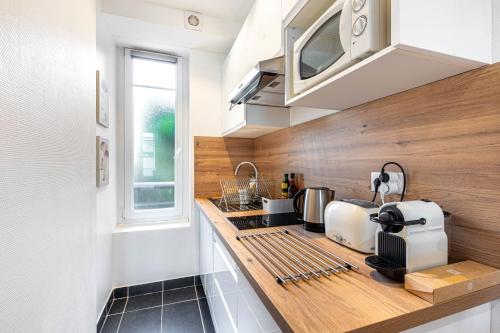 La cuisine est équipée d'un plan de travail, d'un évier et d'un four micro-ondes. dans l'établissement GuestReady - Cosy studio in Saint-Maur-des-Fossés, à Saint-Maur-des-Fossés