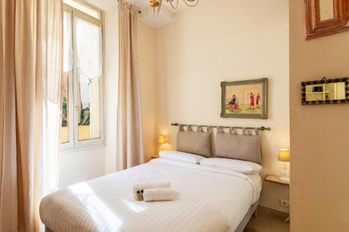 een slaapkamer met een bed met witte lakens en een raam bij Frères Pradignac in Cannes