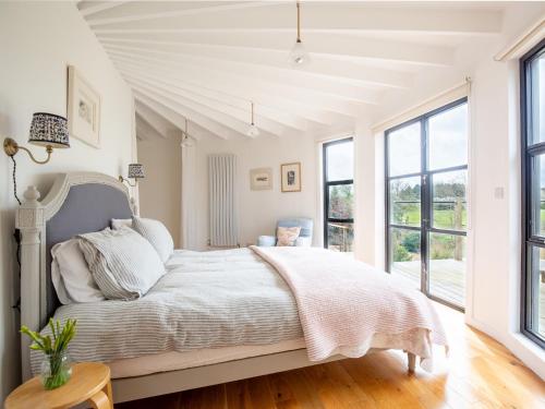 a white bedroom with a bed and windows at The Silo in Chipping Norton