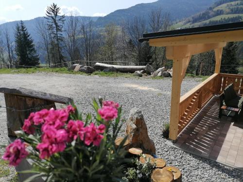a porch with a bench and pink flowers in the foreground at Lärchenhaus ,,Unterer Brodl" in Kammersberg